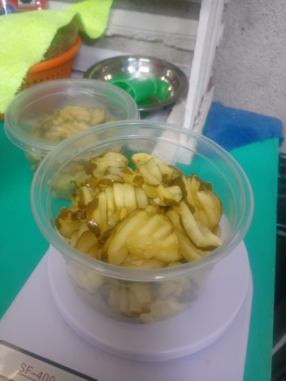 A heaping container of pickles being weighed on a kitchen scale